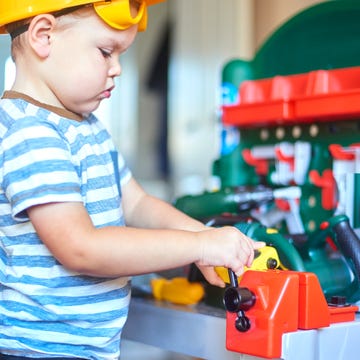 toddler playing with toy work bench and tools