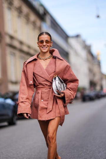 copenhagen, denmark august 8 nina sandbech wears light brown sunglasses, gold earrings, gold chain necklace, sand beige oversized blazer belted mini trench dress, white and black christian dior saddle leather bag, outside gestuz, during the copenhagen fashion week springsummer 2024 2025 on august 8, 2024 in copenhagen, denmark photo by edward berthelotgetty images