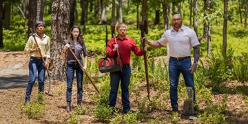 a group of people holding sticks in the woods