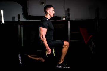 man doing lunge with weights in the gym