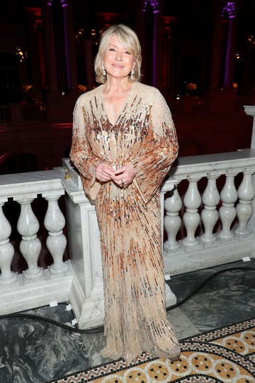 martha stewart smiling for a photographer in front of a decorative railing