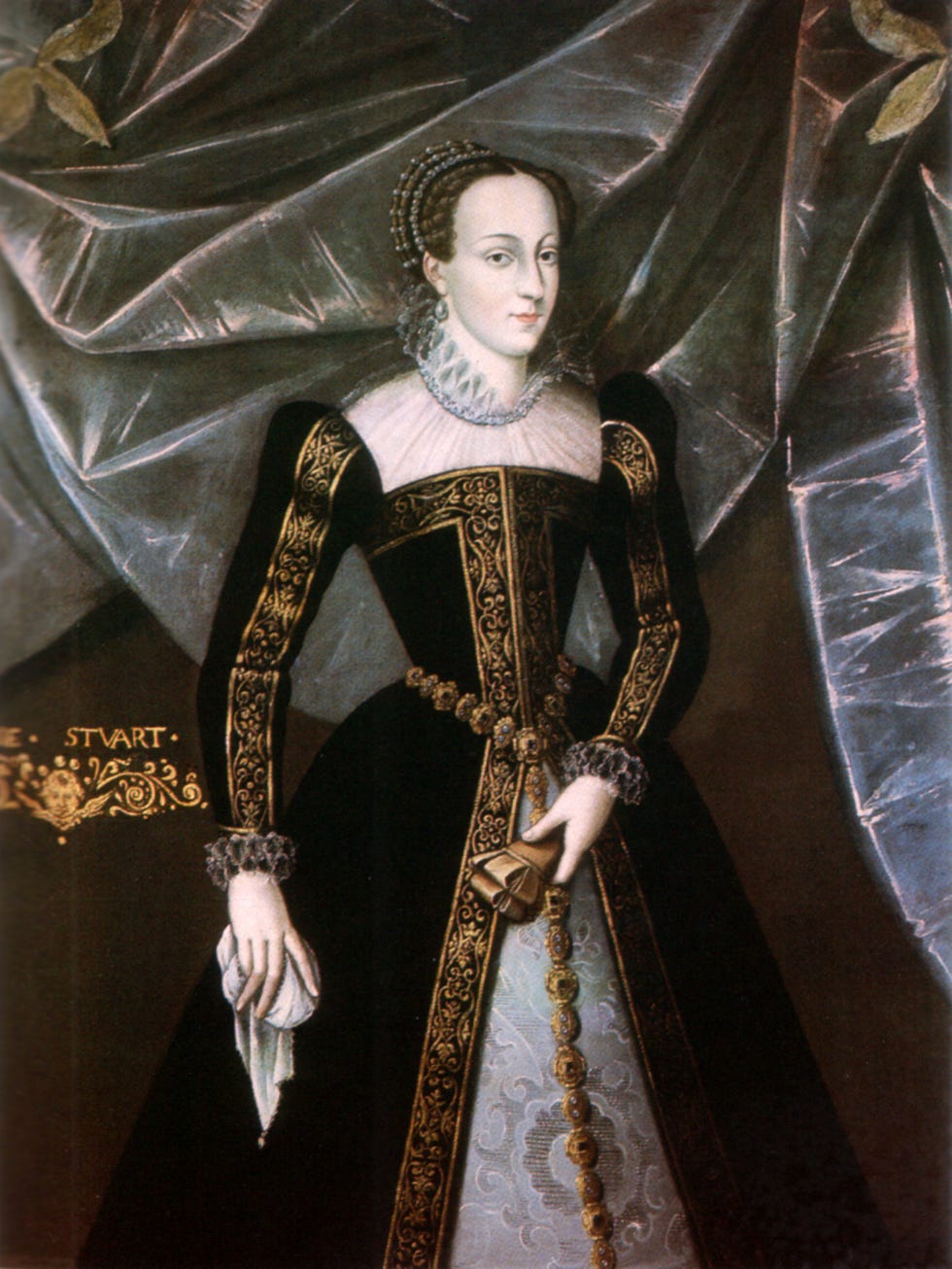 mary, queen of scots stands and wears a black dress with gold trim and a white lace top and collar, she also has on a crown and pearl earrings