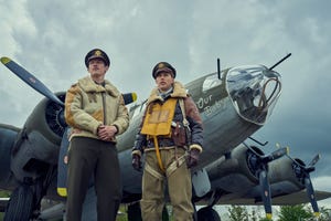 callum turner and austin butler star looking up and off camera while standing in front of bomber planes in a scene from masters of the air