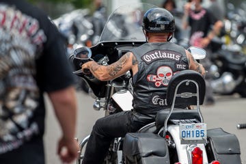 a motorcycle rider wearing a leather jacket with a skull and pistons logo