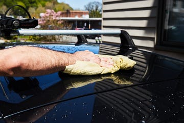 a person drying off a car roof with a microfiber cloth