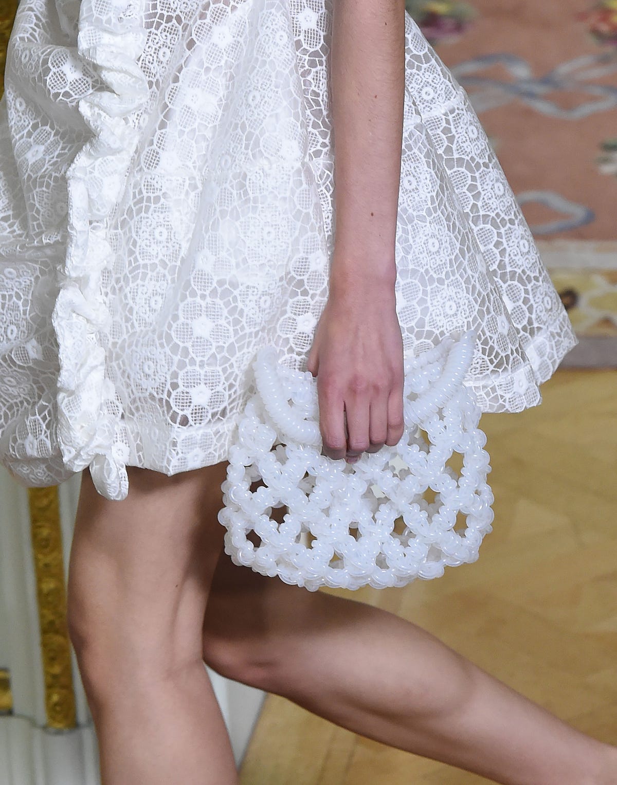 a model carrying a beaded white clutch on the simone rocha runway