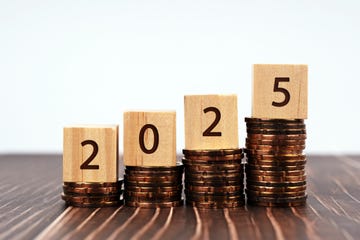 2025 new year resolutions on wood block on top of stack of coins