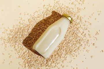 oat milk in glass bottle and oatmeal flakes on beige background healthy vegan non dairy organic drink with flakes lactose free milks in minimal flat lay style top view