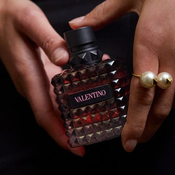 perfume bottle held in a hand featuring a distinct cubic design and branding