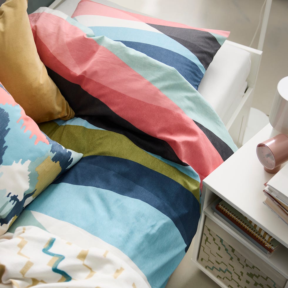 colorful bedding and decorative pillows on a bed with a nightstand