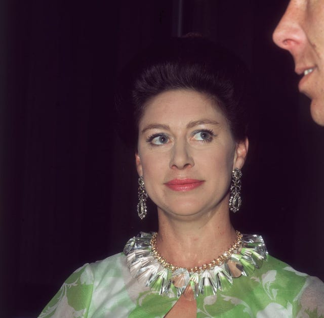 princess margaret looks to the right, she wears matching earrings and necklace with a green and white top
