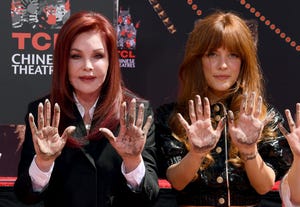 priscilla presley and riley keough look at the camera with their concrete covered palms out