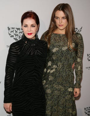 priscilla presley and riley keough embracing in front of a humane society backdrop