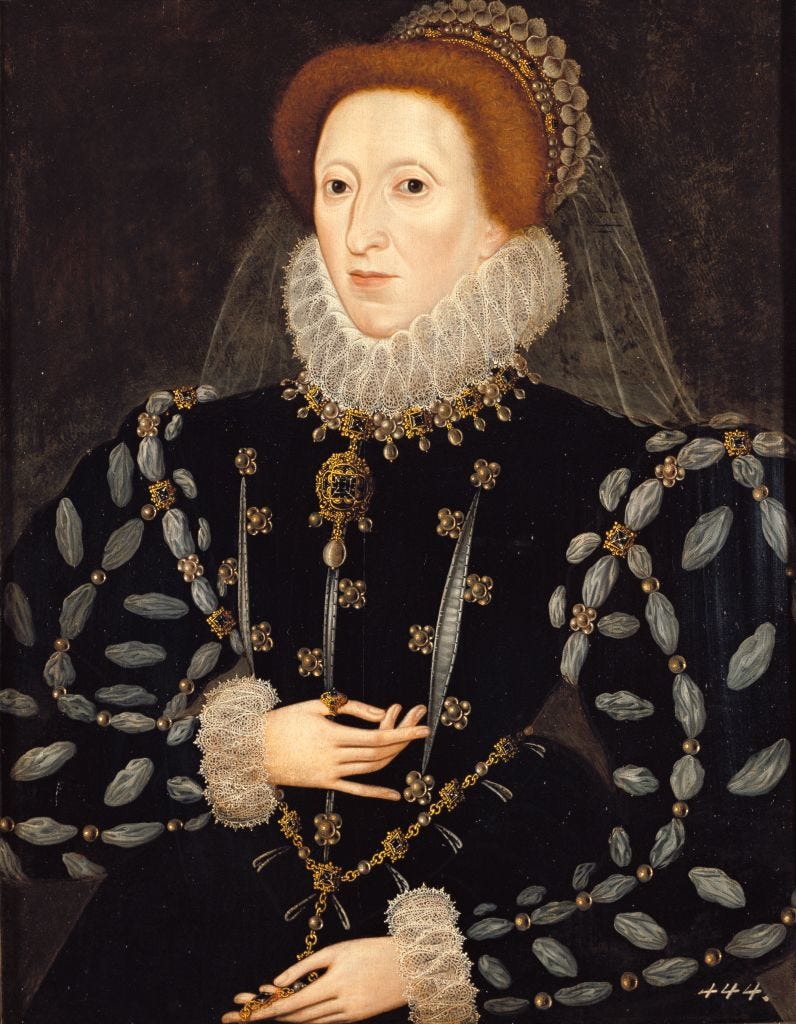 queen elisabeth i wears an ornate black gown with a large white lace collar that covers her neck, her head is topped with a white black and gold crown with a white veil trailing down