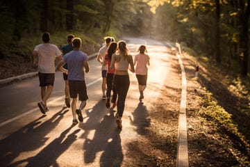 rear view of marathon runners racing at sunset