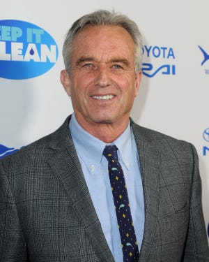 robert f kennedy jr smiles at the camera, he is wearing a gray plaid suit jacket, blue collared shirt, and blue patterned tie