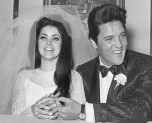 priscilla presley and elvis wearing their wedding attire while smiling and holding hands