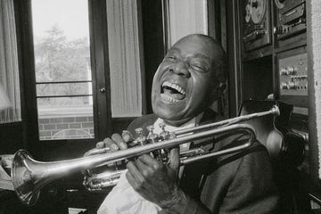 louis armstrong smling while holding his trumpet