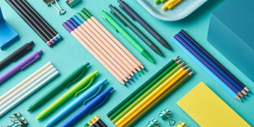 pens, pencils and binder clips on blue background