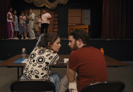 a man and woman sitting at a table in front of a group of people