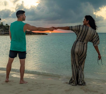 a man and woman holding hands on a beach