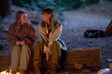 two women sitting on a log together talking