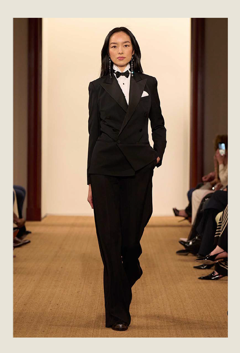 model walking on a runway wearing a black suit