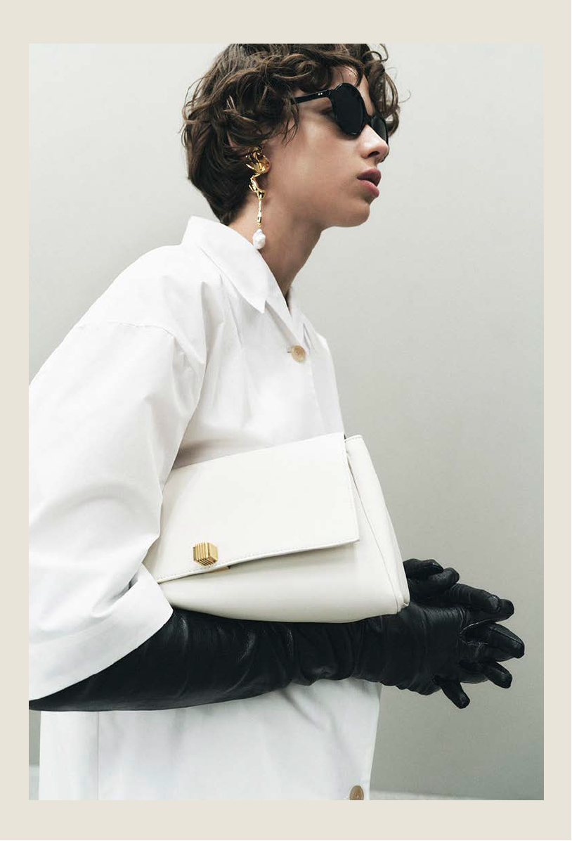 fashionable individual with a stylish white bag and black gloves