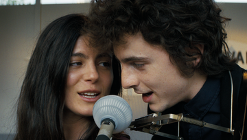 two individuals closely positioned one using a microphone with the background blurred