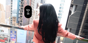 a woman overlooking times square from a hotel balcony