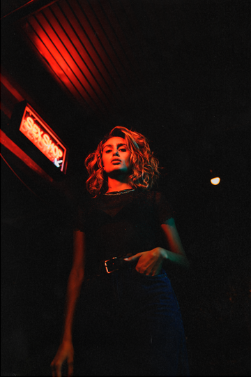 a woman standing in front of a neon sign