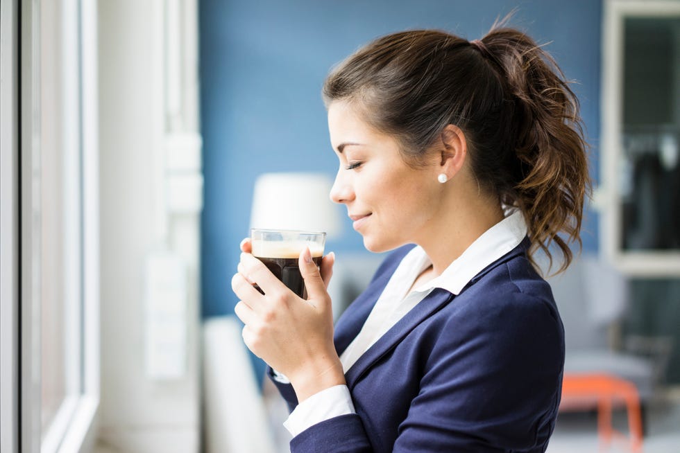 smiling businesswoman enjoying glass of coffee