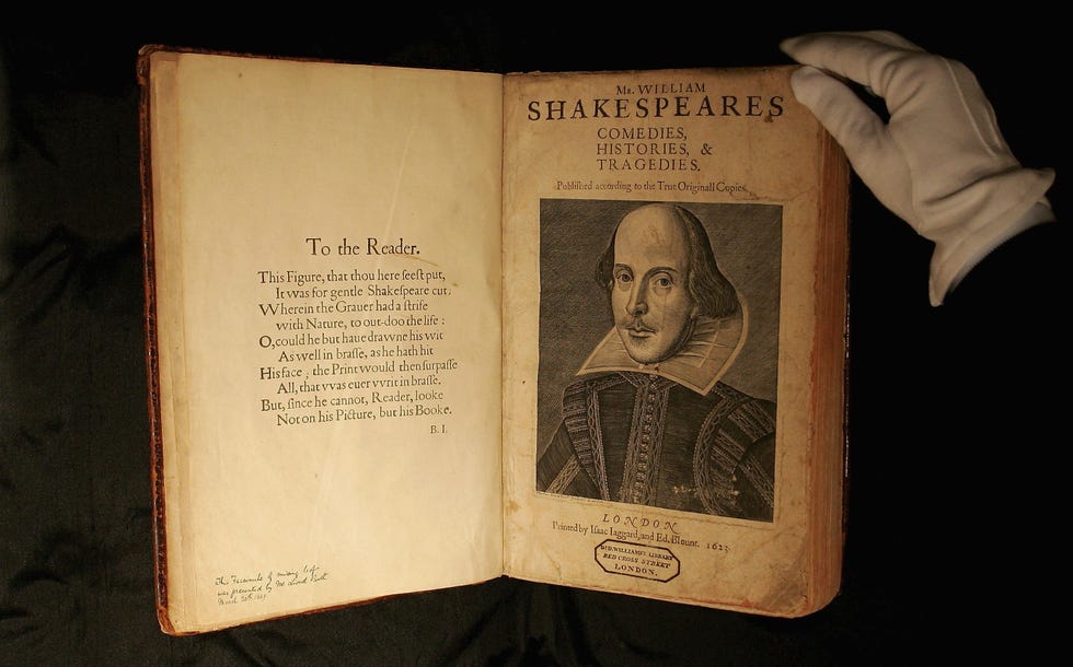 shakespeare’s first folio edition open to the title page with a portrait of william shakespeare on the right page, a white gloved hand touches the top righthand corner of the book