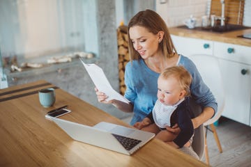 best stay at home mom jobs woman holding baby while looking at paperwork and laptop