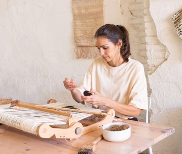 la artesana elisa padron tejiendo sus tapices sobre una mesa de madera