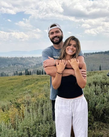 couple embracing outdoors with a scenic mountainous backdrop