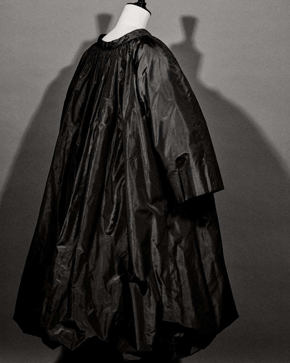 a black and white photo of a mannequin wearing a black coat