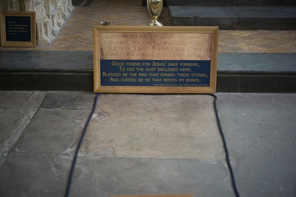 a stone grave site with a framed inscription held above it