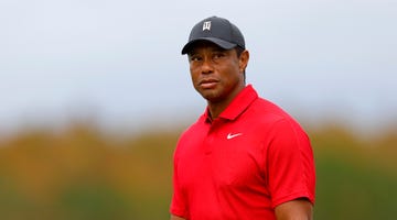 tiger woods wearing a red nike shirt and looking out toward a golf course