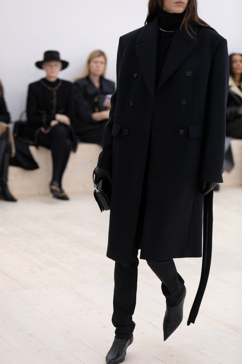 fashion model in a stylish black outfit walking down a runway