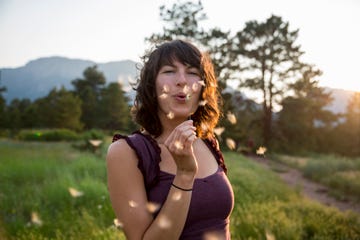 woman blowing dandelion flower