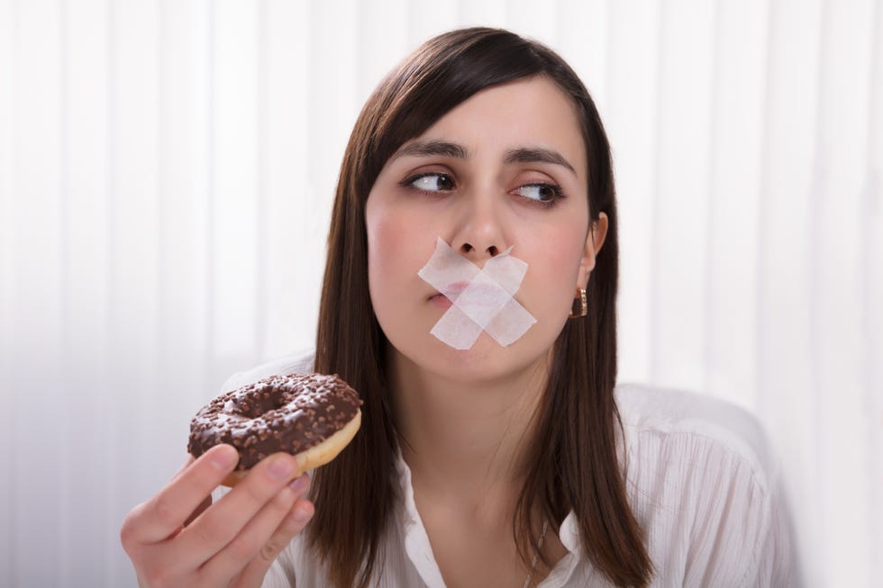 woman with sticky tape over her mouth holding donut