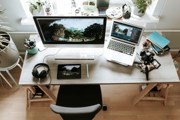 work from home desk with monitor laptop headphones and digital camera