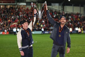 rob mcelhenney and ryan reynolds hold the wrexham trophy