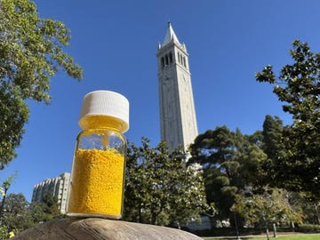 glass jar containing yellow powder in focus with a tall clock tower in the background