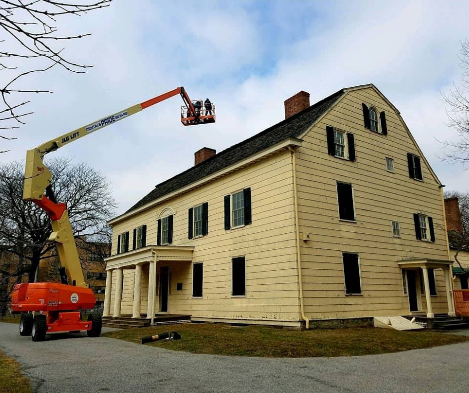 A crane lifting workers to a roof of a house