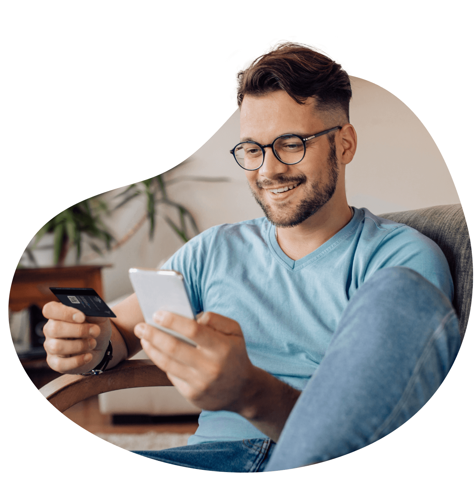 Homem feliz com um celular em uma mão e um cartão de crédito em outra.