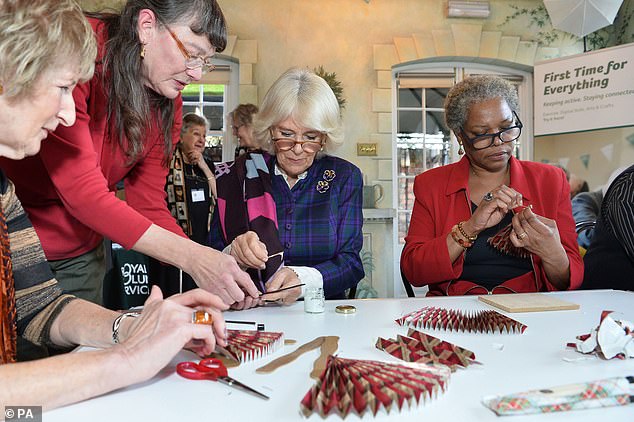 The royal appears in deep concentration as she makes her fan along with volunteers at the London-based museum