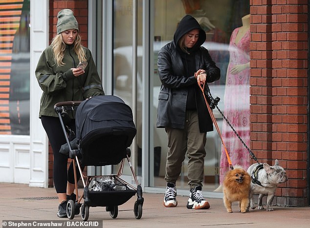 Casual: Her friends dressed down in a black rain mac and a pair of khaki joggers