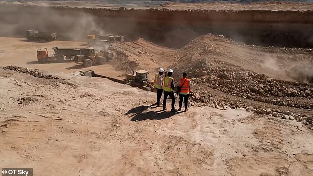 Construction workers stand on the edge of a vast trench being dug for The Line megacity